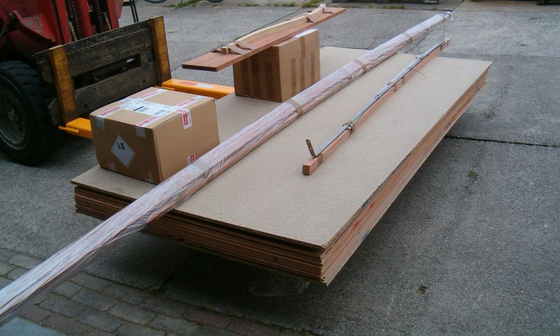 Compleet bouwpakket van de Lobster 12,5 op een pallet met gefreesde platen, massief hout en epoxy