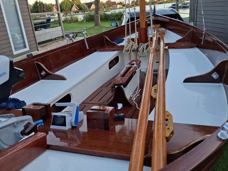 Dek van een Lobster 12,5 met blank gelakte houten mast, giek en gaffel en opgeschoten lijnen