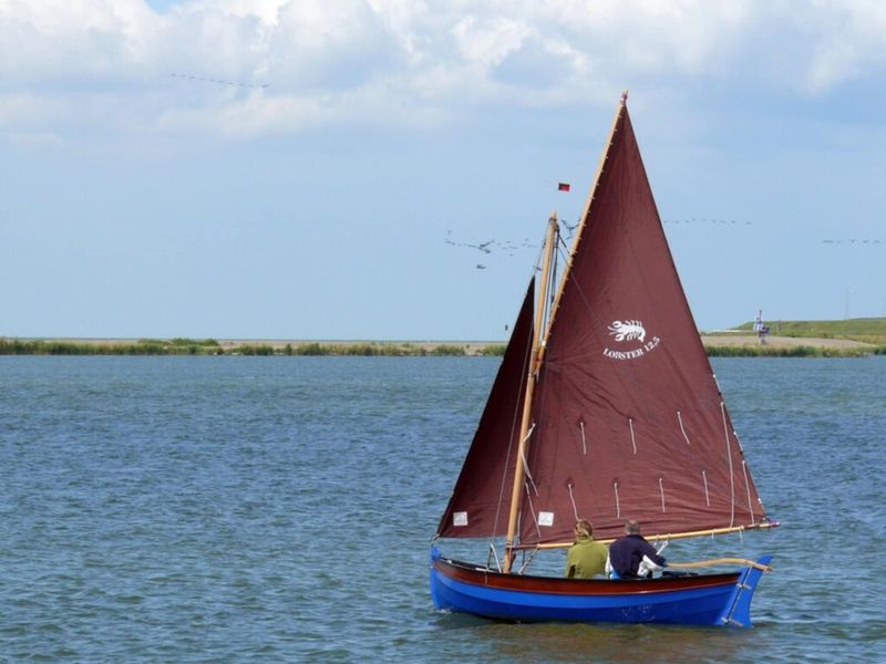 Lobster 12,5 zeilend op ruim water met bruin gaffeltuig waarop de naam Lobster 12.5 staat