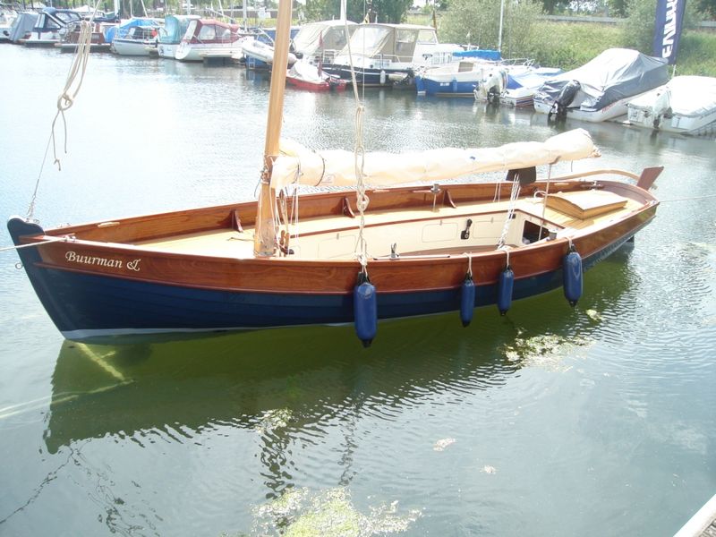 Afgebouwde houten Lobster-sloep met opgedoekt tuig aangemeerd in een haven